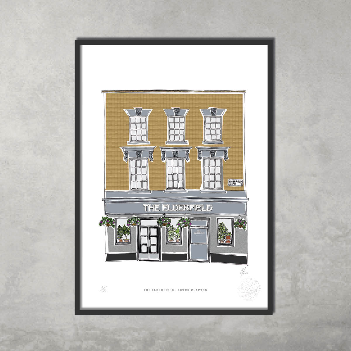 The Elderfield – Limited Edition of 50 by 45 Original: an A3 colour giclée print of this Hackney pub with gold brick facade, three windows, flowers, and sign. Framed and displayed against a gray wall—perfect for collectors.