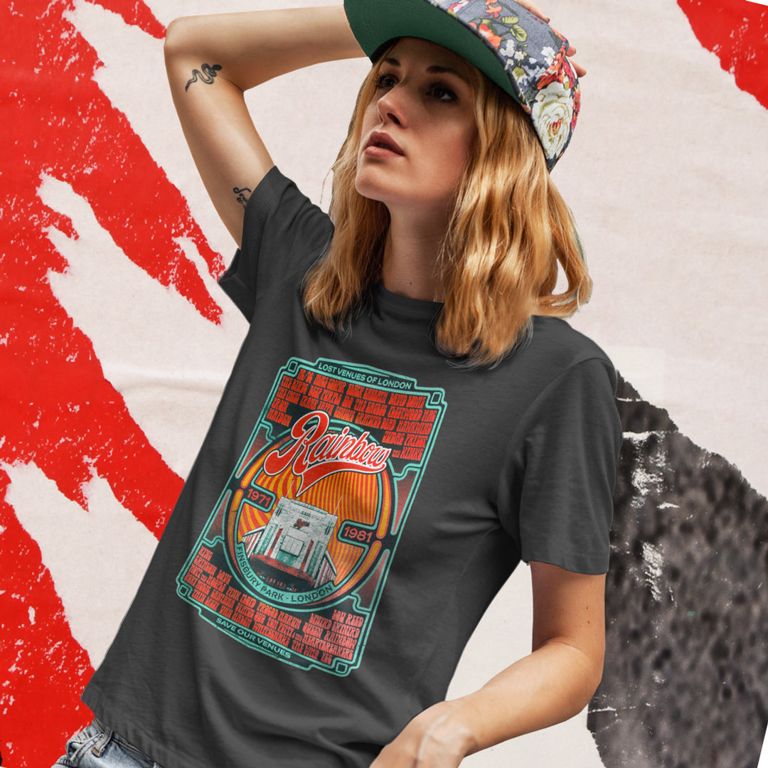 A young person with long blond hair wears a floral cap and the My Store Rainbow Rock T-Shirt—Limited Edition of Only 100—featuring a colorful vintage design against a bold red and white backdrop, perfect for a Rainbow Theatre Retrospective.